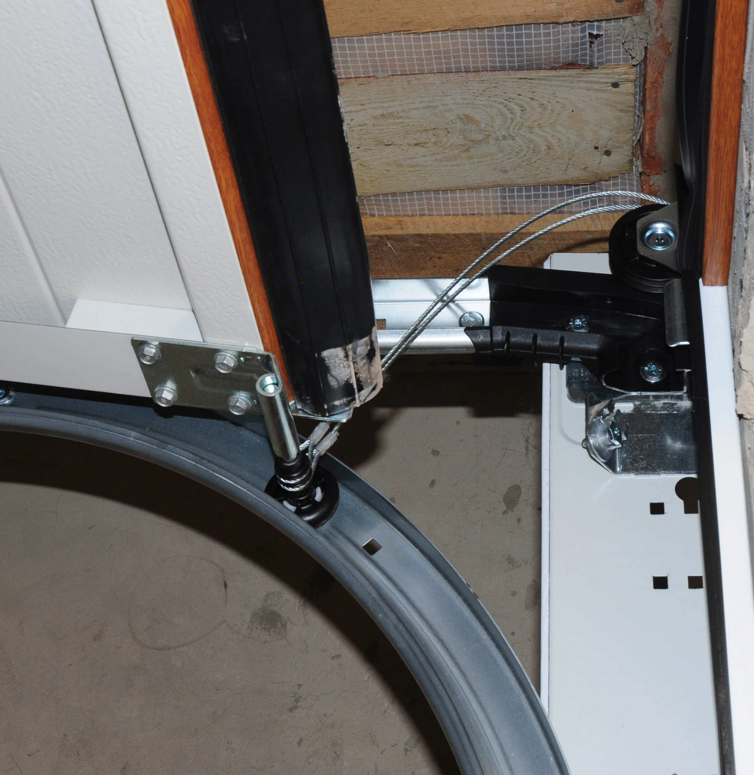 Broken lift cable hanging loose beside the track and bottom fixture