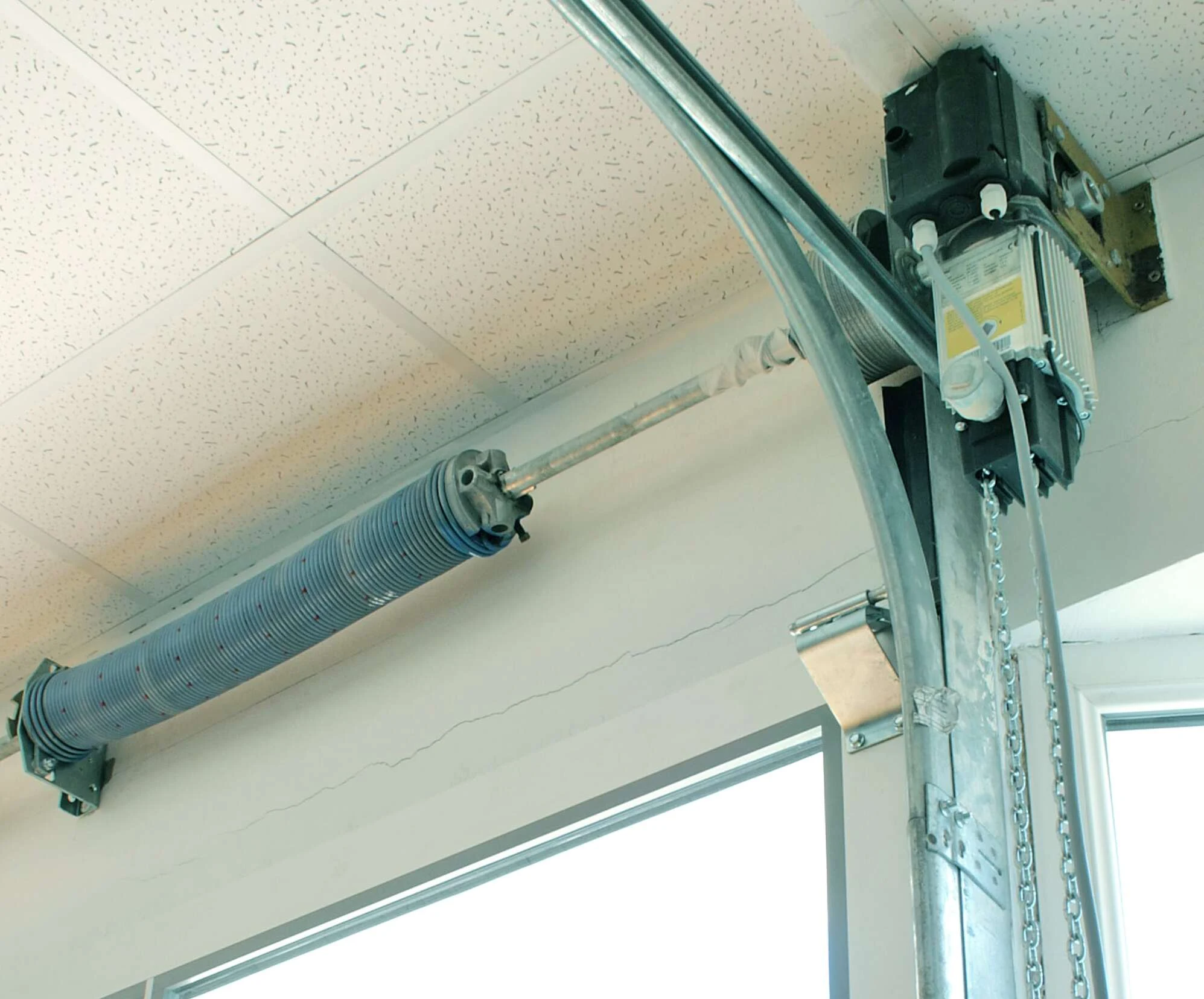 Wall-mounted jackshaft garage door opener beside a torsion shaft