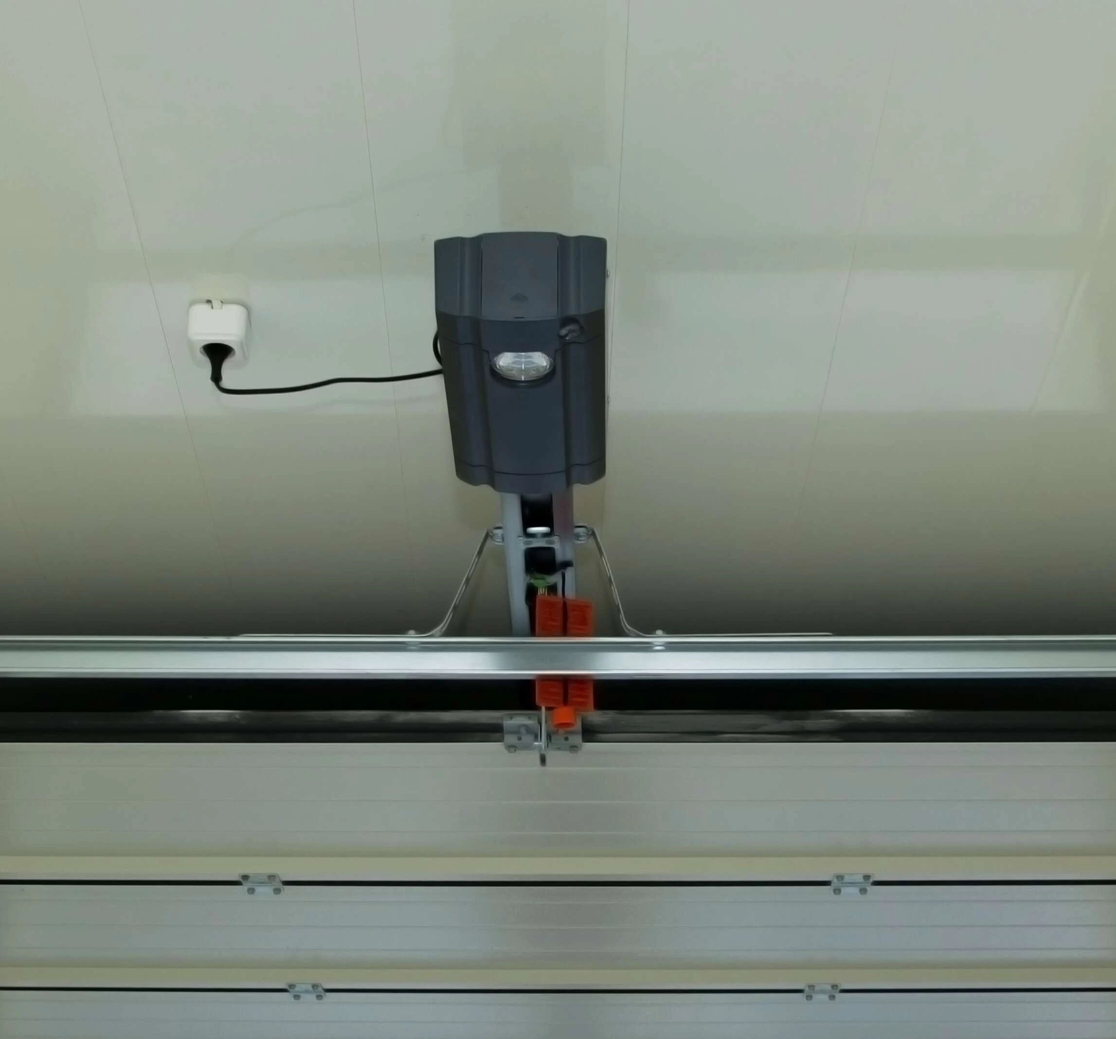 Legacy ceiling-mounted opener and rail above a sectional garage door