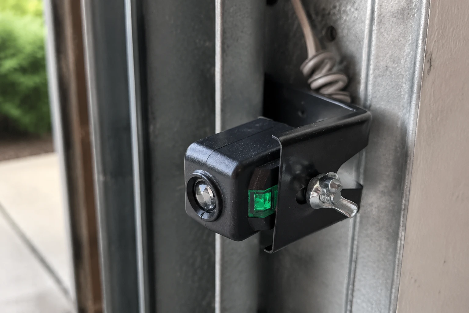 Garage door photo-eye sensor low on the track with its indicator lit