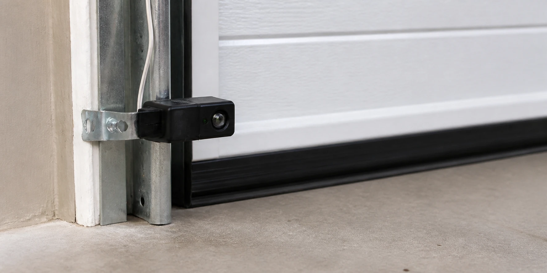 Garage door photo-eye sensor secured beside the track after service