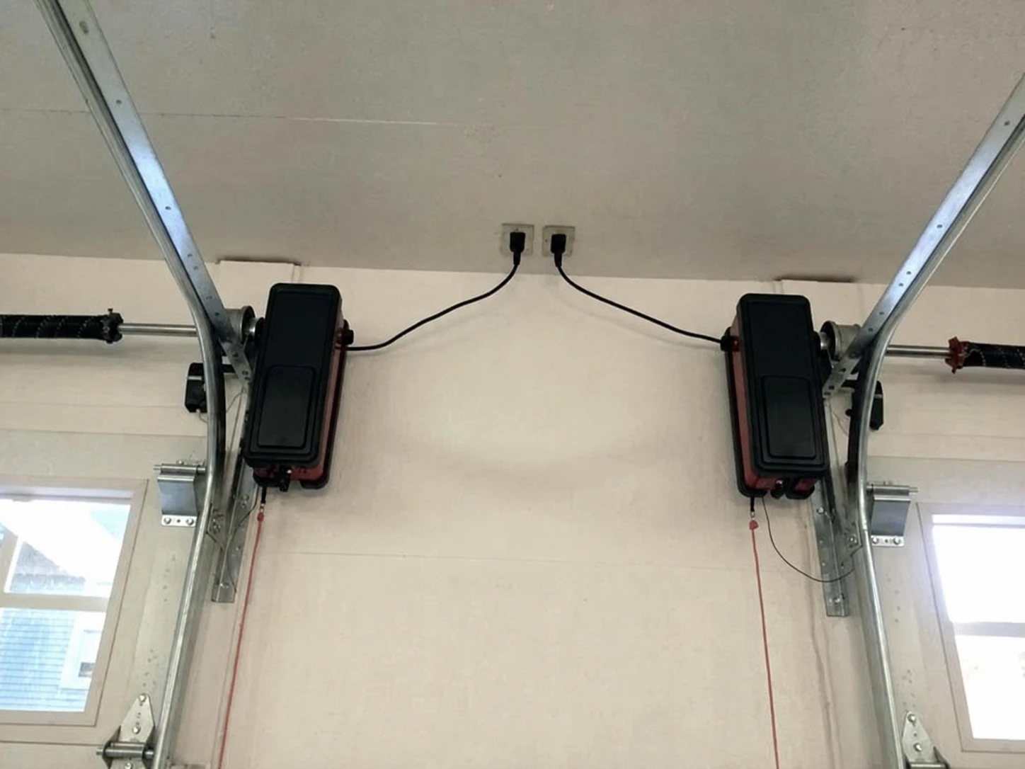 Two wall-mounted jackshaft openers beside their torsion shafts