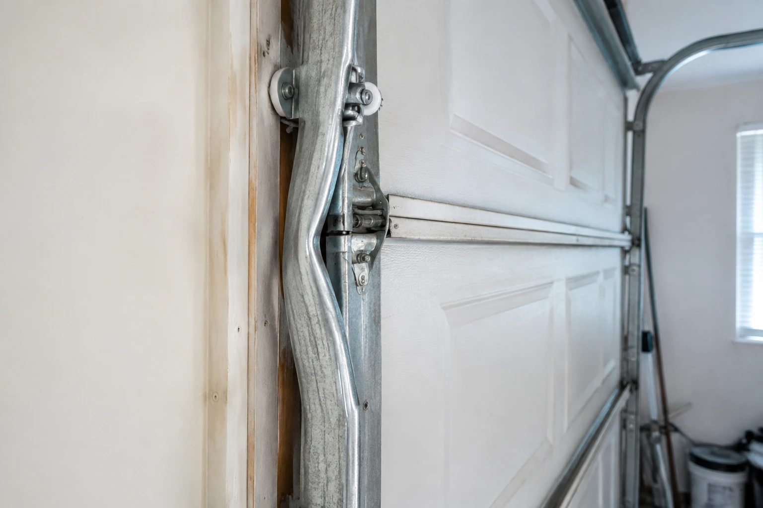 Severely bent vertical garage door track beside a sectional door